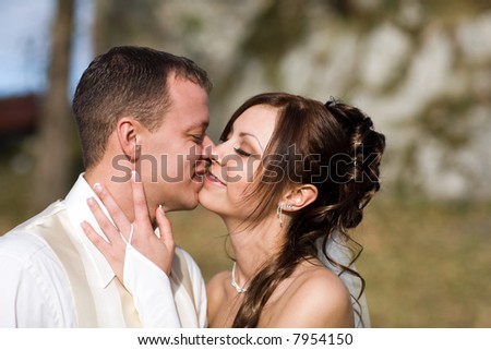 Attractive bridal couple kissing each other tenderly with a slight smile