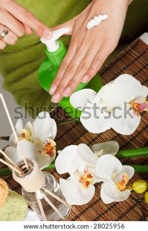 A view of hand lotion being applied to a woman\'s hands.