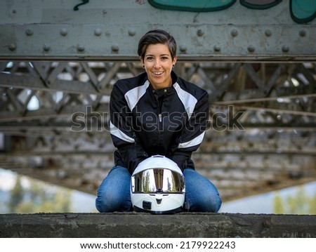 Young happy smiling female motor cyclist kneeling crouching on a wall in a centred pose with her full safety gear Foto d'archivio © 