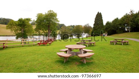 Rest area with many round group tables in a park near a river.