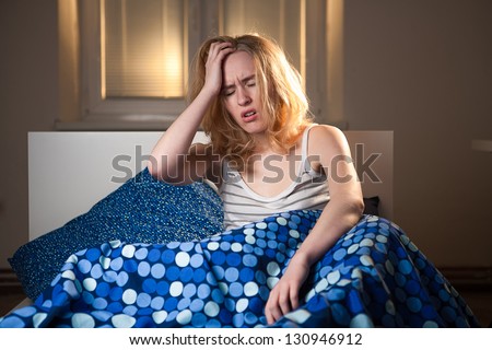 young caucasian woman in bed with headache depression and hangover from early morning waking up, everyone hates early mornings concept