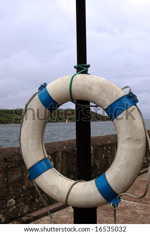 a lifebuoy ring on the dock of a bay with the view of a yacht sailing
