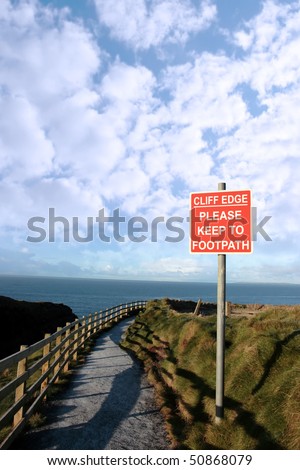 a warning sign of danger at a slippery cliff edge walk