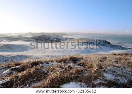 snow covered links golf course in ireland in winter with sea background