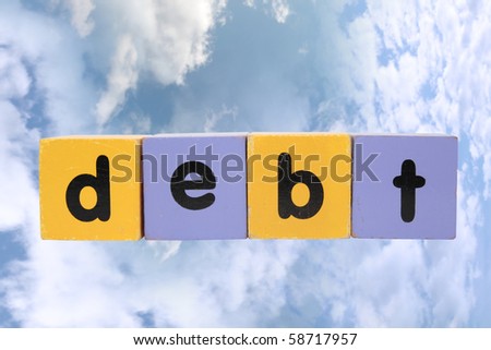 assorted childrens toy letter building blocks against a cloud background that spell debt with clipping path