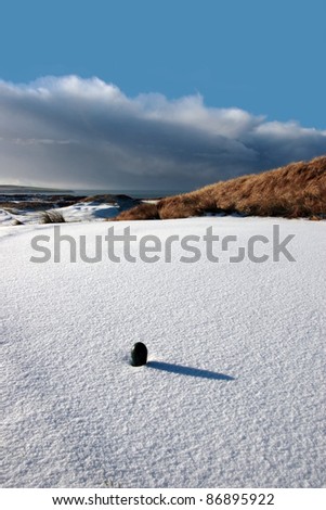 green tee on a snow covered links golf course in ireland in winter