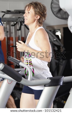 Mature woman running on treadmill at fitness center