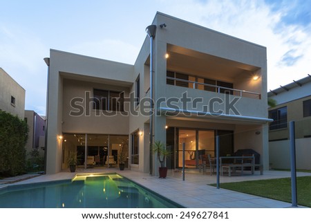 Modern home exterior with pool at dusk