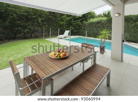 Modern suburban backyard with table setting and swimming pool
