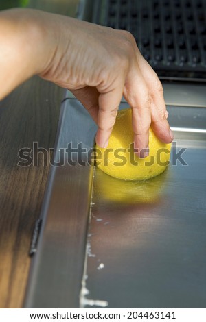Hand using lemon to clean top of electric pan