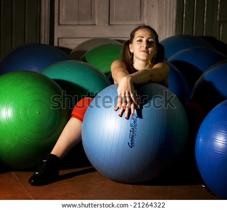 girl is sitting with a ball on the floor in the gym