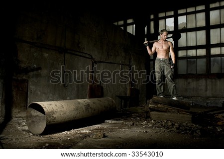 Muscular man with spade in industrial place