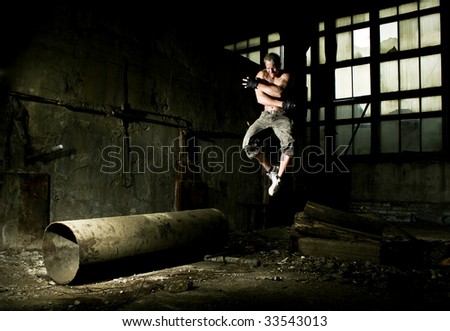 Muscular man jumping in industrial place