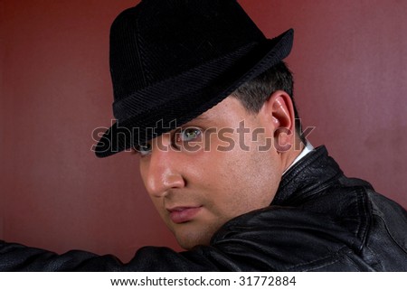 Close-up of a young man in a trilby looking over shoulder