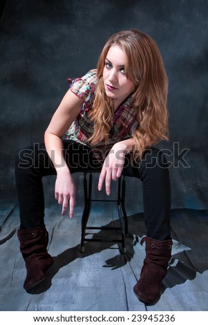 Beautiful dirty-blond girl sitting on stool with attitude