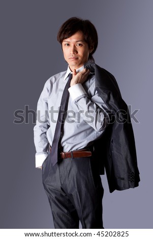 Successful Asian business man standing with confidence and jacket over his shoulder and hand in pocket, isolated.