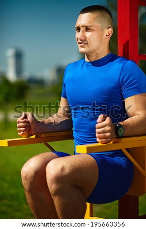 Handsome healthy happy strong athlete male man exercising at the city park - fitness concepts on a beautiful summer day on horizontal bar