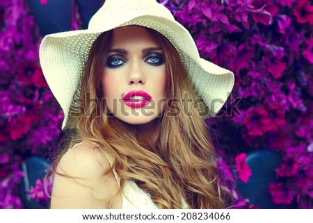 High fashion look.glamor closeup portrait of beautiful sexy stylish blond young woman model with bright makeup and pink lips with perfect clean skin in hat near summer flowers