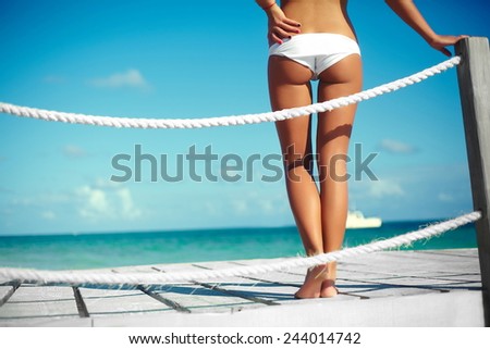 High fashion look. back of glamor sexy sunbathed model girl in white lingerie  behind blue beach ocean water on pier