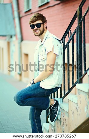 Funny smiling hipster handsome man guy in stylish summer cloth in the street in sunglasses