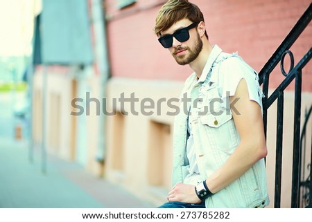 Funny smiling hipster handsome man guy in stylish summer cloth in the street in sunglasses