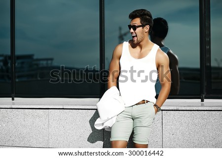 funny smiling young sexy handsome muscled model man in casual cloth in sunglasses in the street