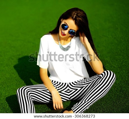 Funny crazy glamor stylish sexy smiling beautiful  young woman model in hipster clothes sitting in the grass in the park