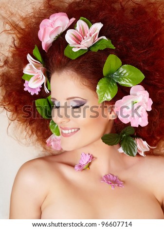 closeup portrait of beautiful smiling redhead ginger woman face with colorful flowers in hair in profile