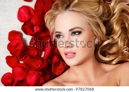 closeup portrait of beautiful blond dreaming girl with red roses long curly hair and bright makeup