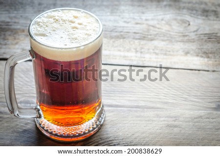 Mug with dark beer on the wooden table