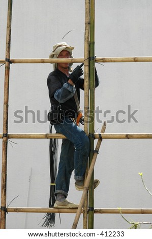 A construction worker erecting bamboo scaffolding at a building construction site in Hong Kong.