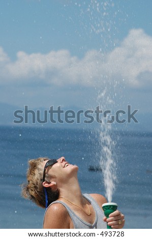 a hose pipe gushing water on a woman on a hot, sunny day