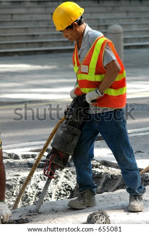 Road worker on a sidewalk with a jackhammer digging up concrete