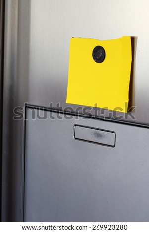 Blank yellow  paper and magnet on refrigerator door.