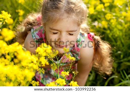 Little blonde girl inhales scent of wild flowers