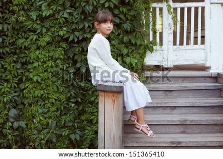 Beautiful little girl in dress sitting on the porch