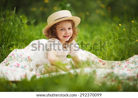 Little happy girl is sitting and resting on the grass