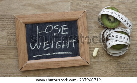Lose weight written on a chalkboard next to a kiwi an inches