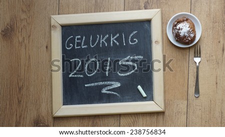 Happy 2015 in Dutch written on a chalkboard next to a Dutch donut