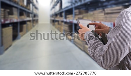 Businessman with touchscreen tablet checking inventory in stock room. Store house inspection
