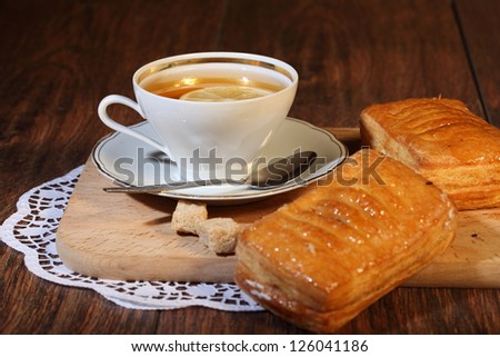 Still-life, cup of fragrant tea with a lemon and sugar and tasty appetizing puff pies