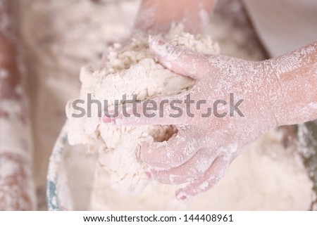 The hands kneading dough for a batch of pies, pies and various products from the test