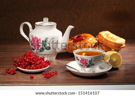 Pleasant tea drinking, fragrant fresh tea with a juicy lemon, a ripe bright red currant both an appetizing cheese cake and a puff pie