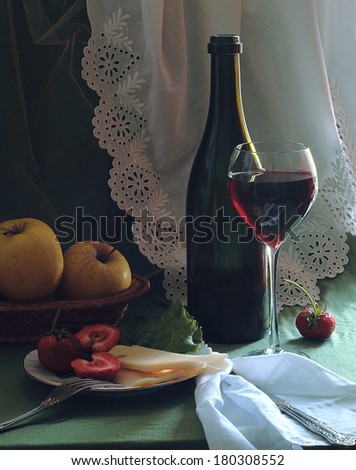Still-life with red wine a fresh strawberry and apples and cheese, fragrant red wine in a graceful glass and juicy apples in a wattled vase and a fresh strawberry with cream cheese on a plate