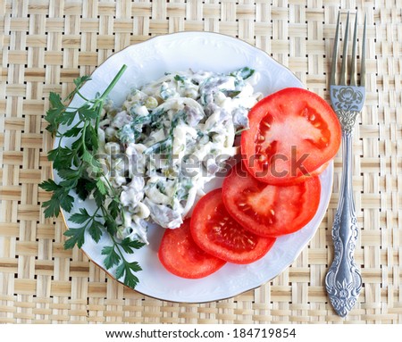 Still-life with salad the filled mayonnaise and fresh tomatoes, salad from boiled vegetables and marinaded peas filled with mayonnaise both decorated with parsley and a fresh tomato cut by circles