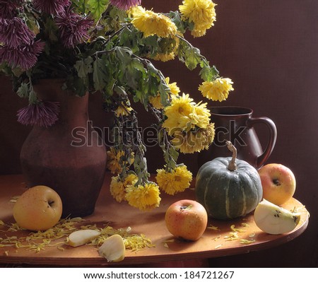 Still-life with fresh fruit and a bright bouquet, a magnificent bouquet from yellow chrysanthemums in a clay jug and fresh fragrant ripe juicy apples