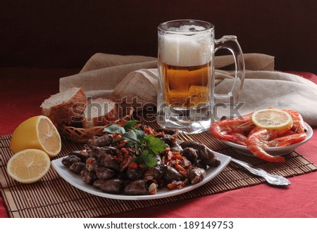 Still-life with beer and shrimps and fried chicken hearts, fragrant fresh beer submitted with royal shrimps both a juicy lemon and appetizing fried chicken hearts with vegetables