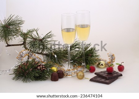 Still-life with wine glasses with champagne both gold spheres and red apples and a chocolate bar, a New Year\'s still-life