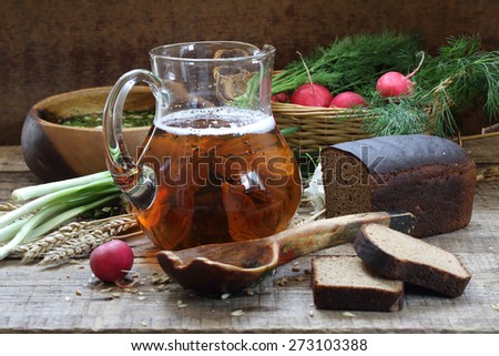 Jug with kvass, rye bread and okroshka in a wooden bowl