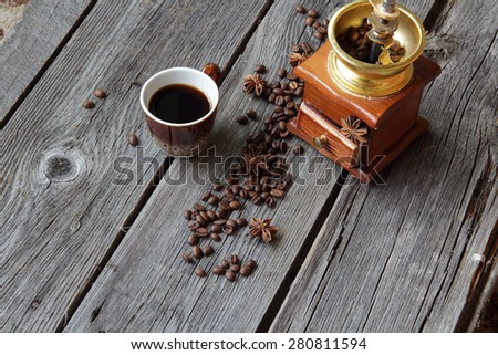 Cup of coffee and manual coffee grinder on a wooden background